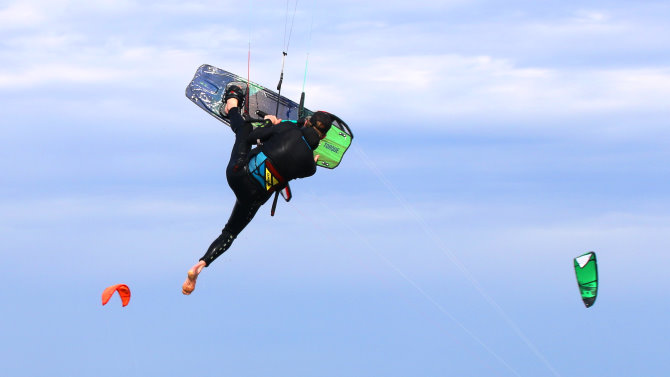 Click to go to the kiteboarding blog A kiteboarder jumps high into the air